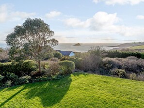 A coastal landscape with a grassy lawn, a tree, and a view of the sea. - 4 Bed in Wembury (oc-54383) (Wembury)
