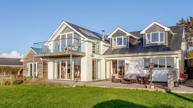 A two-story house with a balcony, large windows, and a well-maintained lawn. - 4 Bed in Wembury (oc-54383) (Wembury)