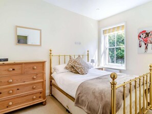Ein Schlafzimmer mit Bett, Kommode, Fenster und Bildern.