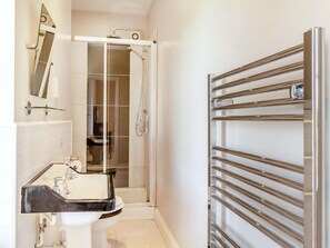 Ein Badezimmer mit einer Duschkabine, einem Waschbecken mit Spiegel und einem Handtuchhalter.