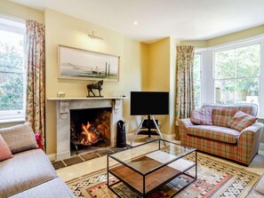 Ein Wohnzimmer mit Kamin, einer Couch, einem Glastisch und einem Fernseher.