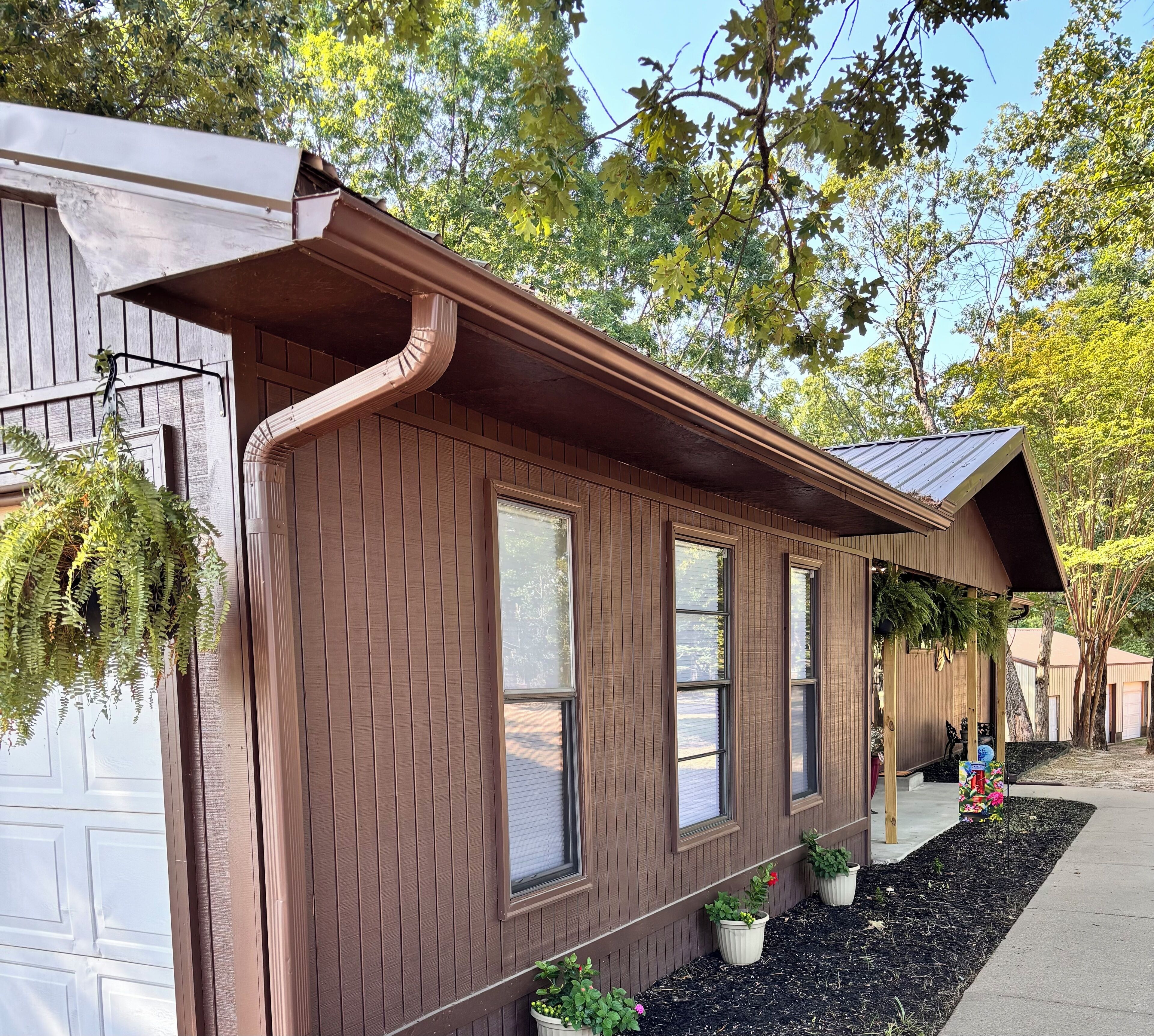 Una casa de madera con techo inclinado, varias ventanas y macetas con plantas a lo largo de la fachada.