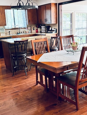 A kitchen with wooden cabinets, a central island, and a dining table with chairs.