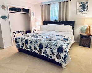 A bedroom with a bed, a nightstand, a lamp, a chair, and a wardrobe.
