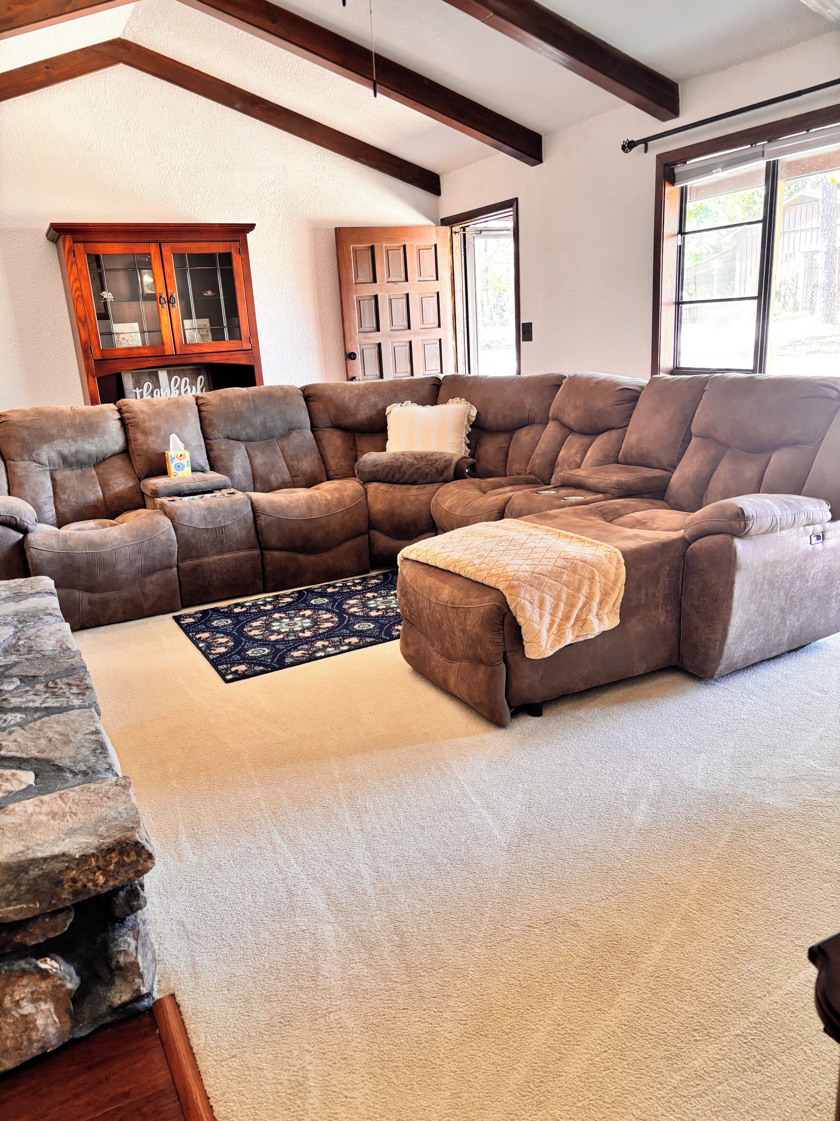 Ein Ecksofa mit Überwurfdecke, ein gemustertes Teppich und eine Wand mit Steinverkleidung.
