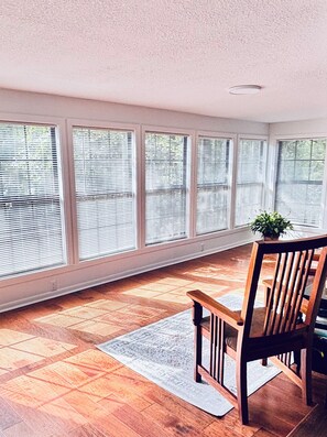 A room with large windows, a wooden floor, and a chair.