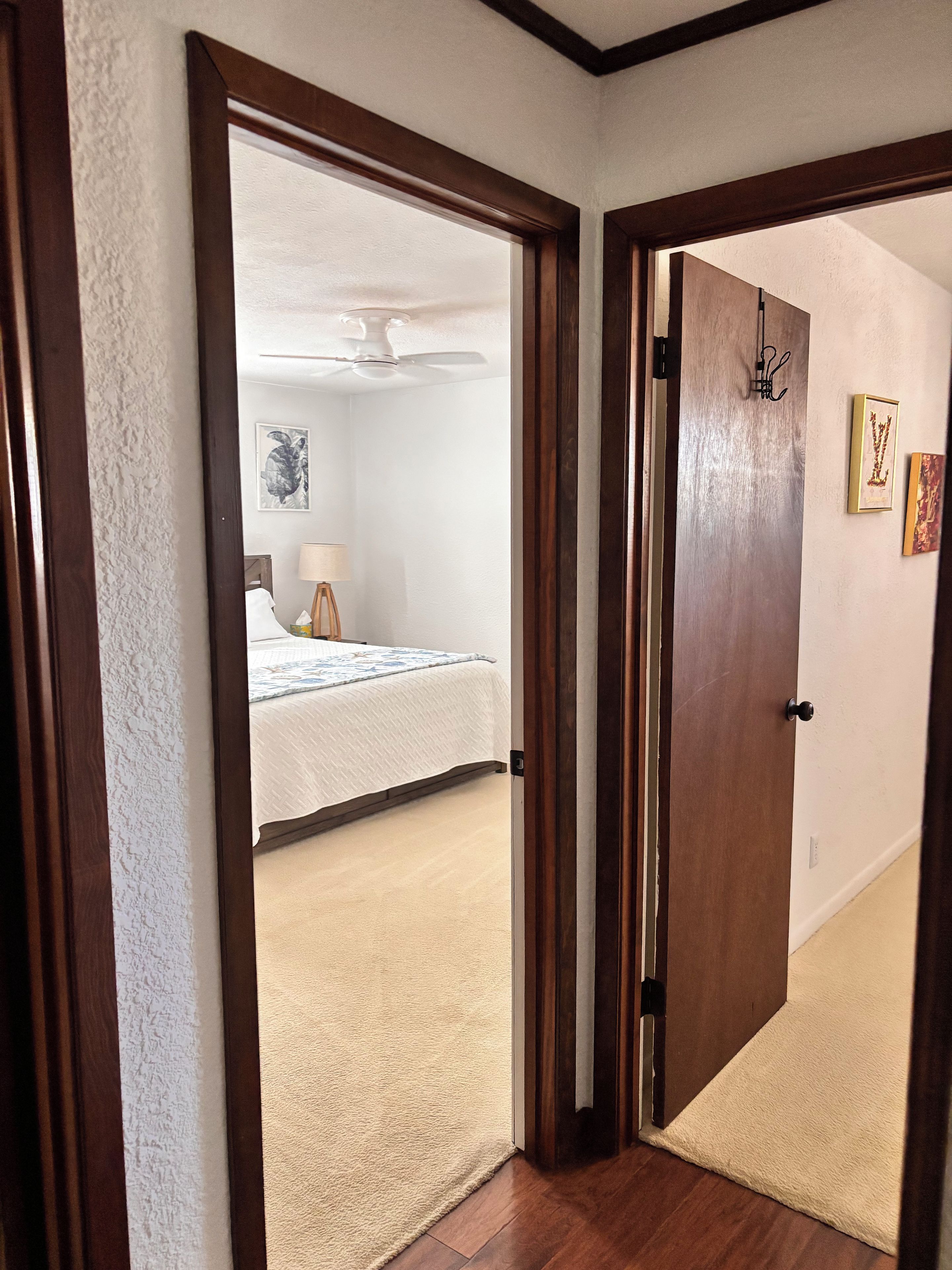A bedroom with a bed, a ceiling fan, and a door leading to another room.