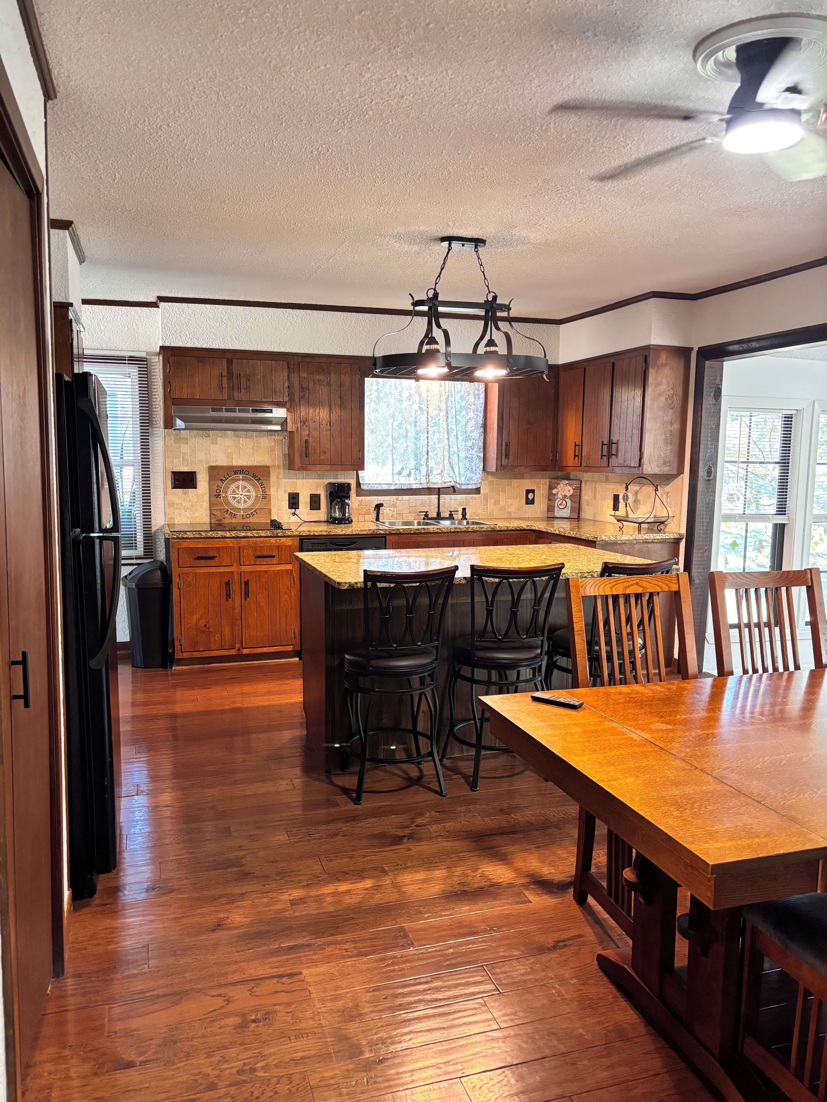A spacious kitchen with wooden cabinets, a central island with bar stools, and a dining table.