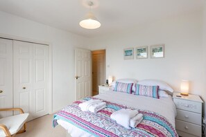 A bedroom with a bed, bedside tables, a chair, and a door.