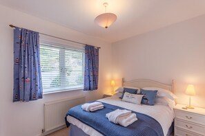 Ein Schlafzimmer mit einem Bett, Nachttischlampen, einem Heizkörper und Vorhängen.