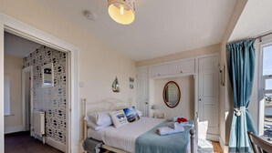 Een slaapkamer met een bed, een raam met gordijnen, een radiator en een muur met een decoratief patroon.
