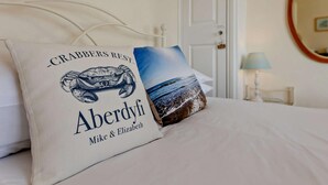 Een bed met twee kussens, waarvan één met een zeeschildpad dessin en tekst, en het andere met een strandafbeelding.