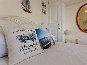 A bed with two pillows, one with a sea turtle design and text, and another with a beach scene. - 2 Bed in Aberdyfi (oc-dy006) (Aberdovey)