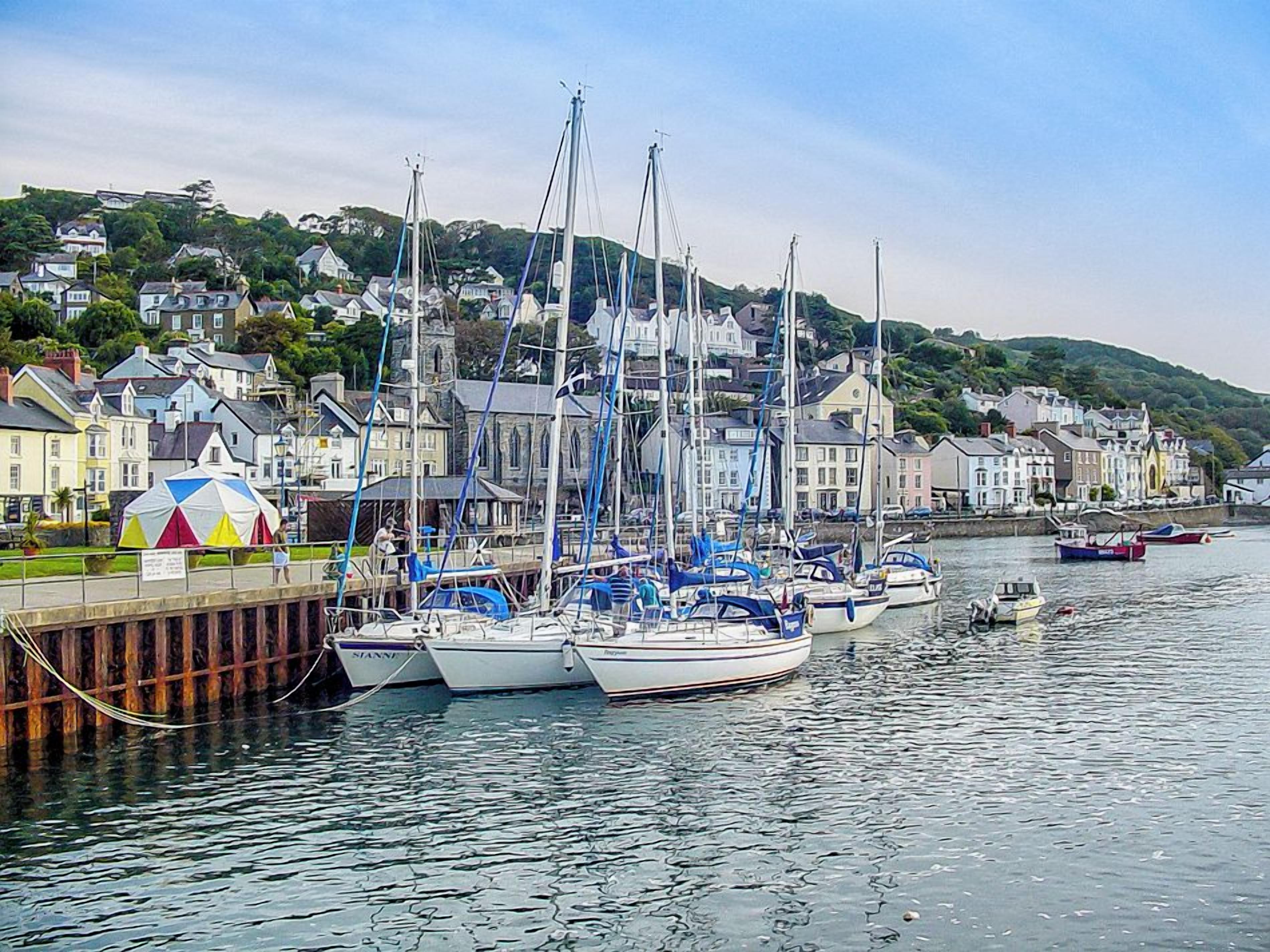 A harbor with several boats docked, a pier, and buildings in the background.