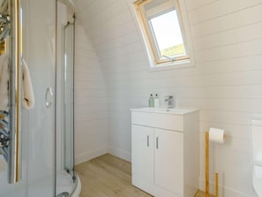 A bathroom with a shower, a sink with toiletries, and a skylight.