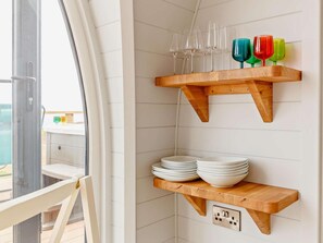 Une cuisine avec des étagères en bois où sont rangées des assiettes et des verres.