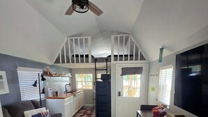 A loft-style living space with a dining area, kitchenette, and a ceiling fan.
