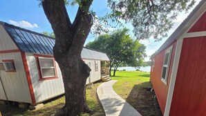 A pathway leading to a row of cabins with a large tree in the foreground.