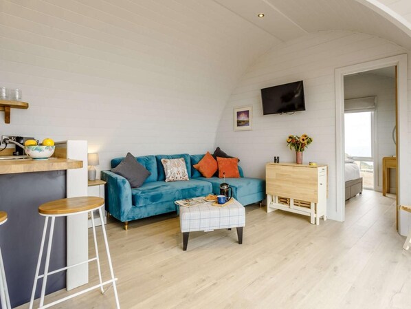 A compact living space with a sofa, coffee table, and a kitchenette area.
