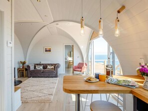 A modern interior with a curved ceiling, a wooden dining table, and a cozy seating area.