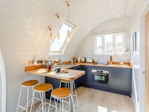 A modern kitchen with a skylight, bar stools, and a built-in oven.