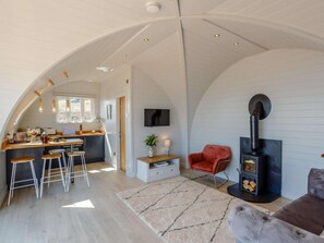 A spacious loft with an open kitchen, a cozy seating area with a fireplace, and a large arched ceiling.
