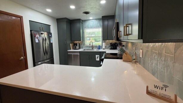 A modern kitchen with dark cabinets, a white countertop, and a built-in oven. - Touchdown on Terrace - Gator Retreat 1 mile to UF - Sleeps 6. (Gainesville)