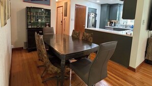 A dining area with a wooden table and chairs, a kitchen with a refrigerator and cabinets, and a display cabinet with items. - Touchdown on Terrace - Gator Retreat 1 mile to UF - Sleeps 6. (Gainesville)