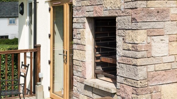 Eine Steinsichtfassade, eine Holztür und ein Tisch mit Glasplatte.
