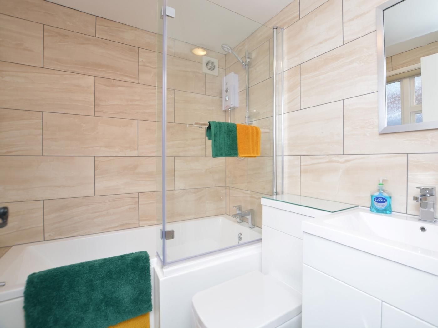 A bathroom with a bathtub, a glass shower enclosure, a sink with a mirror, and a toilet.