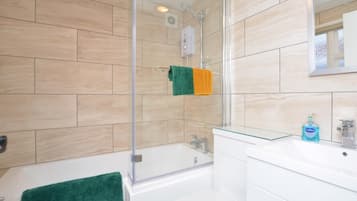 A bathroom with a bathtub, a glass shower enclosure, a sink with a mirror, and a toilet.