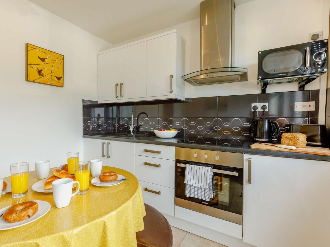 A compact kitchen with a dining area, featuring a microwave, oven, and a coffee maker.