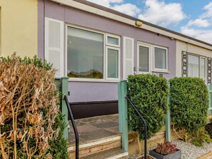 A residential building with a front entrance, a small garden area with a hedge, and a pathway leading to the entrance. - 2 Bed in Brixham (oc-89000) (Brixham)