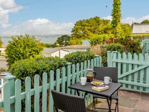 An outdoor seating area with a table and chairs, a view of the city, and a green fence. - 2 Bed in Brixham (oc-89000) (Brixham)