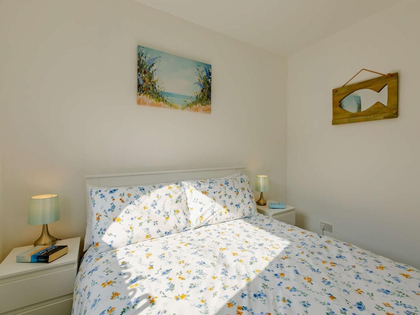 Ein Schlafzimmer mit einem Bett, einem Nachttisch mit Lampe, einem Wandspiegel und einem Bild.
