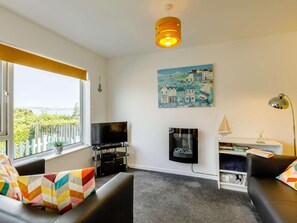 A living room with a TV, a painting, a lamp, and a view of the outdoors. - 2 Bed in Brixham (oc-88998) (Brixham)