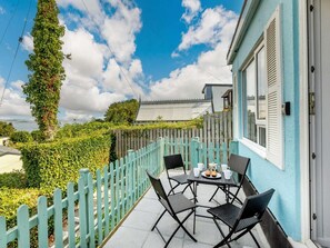 A patio with a table and chairs, a wooden fence, and a building with shutters. - 2 Bed in Brixham (oc-88998) (Brixham)