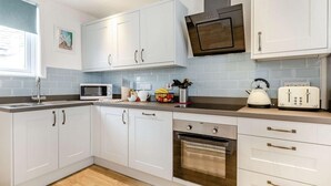 Una cucina moderna con mobili bianchi, un forno a microonde, un bollitore, un tostapane e un forno.