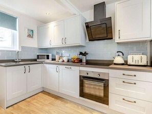 Eine moderne Küche mit weißen Schränken, einer Mikrowelle, einem Wasserkocher, einem Toaster und einem Backofen.