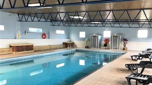Ein Innenpool mit gefliestem Boden, Rettungsringen und einer überdachten Dachkonstruktion.