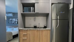 Una cucina compatta con frigorifero in acciaio inossidabile, un forno a microonde e pensili in legno.