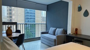 Una camera d'albergo moderna con un balcone, un divano, una scrivania e un letto.