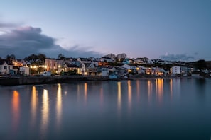 Eine Küstenstadt im Abenddämmerung, Gebäude spiegeln sich im ruhigen Wasser.