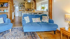 A cozy living room with a blue sofa, a patterned rug, and wooden beams. - 3 Bed in Brecon (oc-bn065) (Crai)