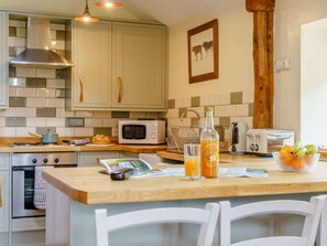 Una cocina con encimera de madera, microondas, hervidor y tostadora.