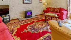 A living room with a fireplace, red sofa, and a patterned rug. - 3 Bed in Brecon (oc-bn065) (Crai)