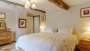 A bedroom with a bed, wooden dresser, bedside tables, and framed pictures on the walls. - 3 Bed in Brecon (oc-bn065) (Crai)