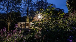 Een tuin met een houten terras en een ster-vormige lamp.