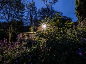 A garden with a wooden deck and a star-shaped light fixture.