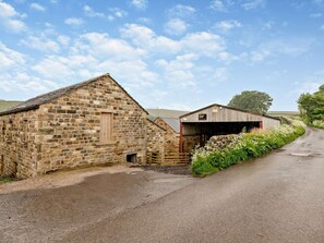 A rural stone building with a wooden door and a covered area with a sign. - 3 Bed in Harrogate (oc-94743) (Pateley Bridge)